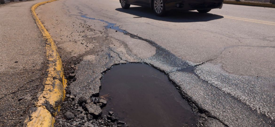 Car driving by a pothole